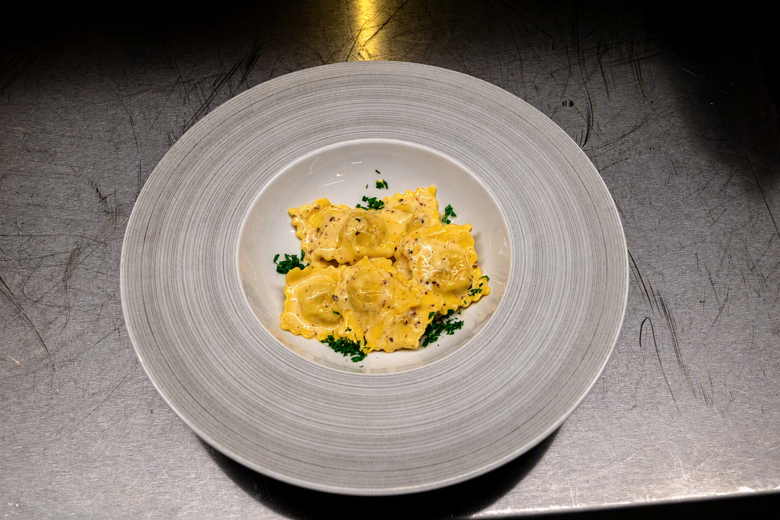 Fem ravioli i lys trøffelsaus med finhakket persille på hvit tallerken